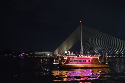 Illuminated boat in river against sky at night