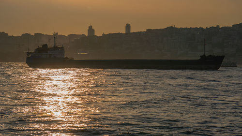 Silhouette boat sailing on sea against sky during sunset