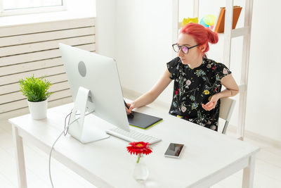 Young woman using phone while sitting on table