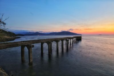 Pier over sea against sky during sunset