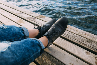 Low section of man relaxing on pier at sea