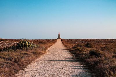 Lighthouse at coastline against clear sky