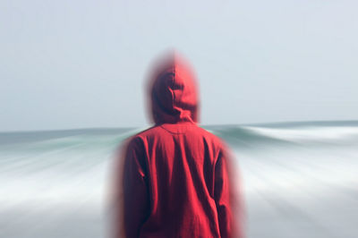 Rear view of woman standing at beach against sky