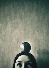 High section of woman with apple on head against wall