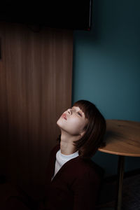 Woman looking up while sitting by table at home