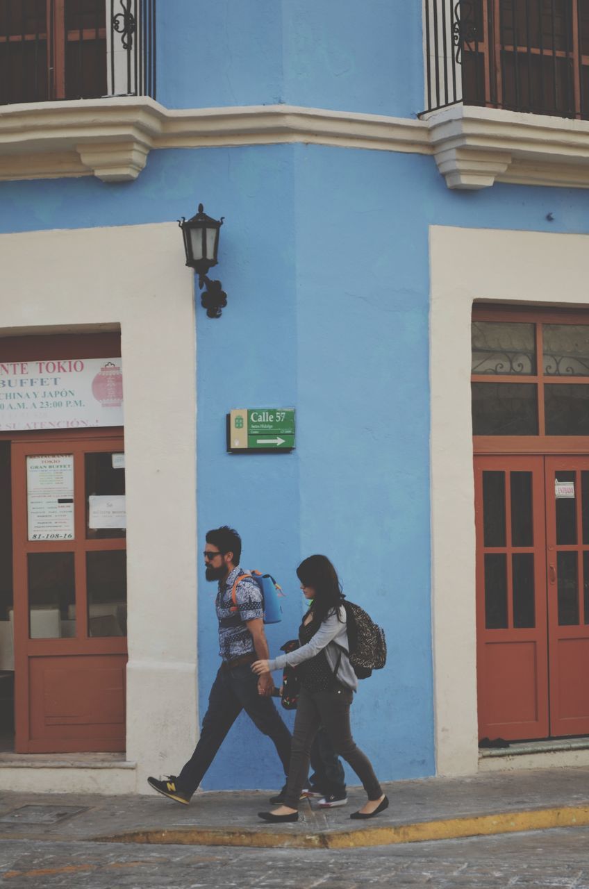 building exterior, architecture, full length, built structure, lifestyles, leisure activity, casual clothing, men, rear view, side view, city, person, standing, street, building, walking, city life, holding