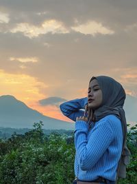 Side view of young woman looking at sunset