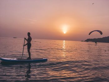 Silhouette person on sea against sky during sunset