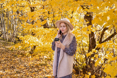 Young woman standing by yellow autumn leaves