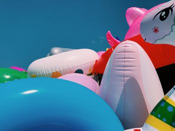 Close-up of various inflatables beach toys on beach against clear summer sky.