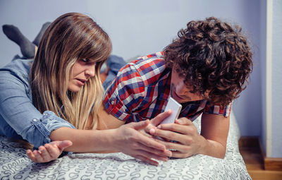 Couple using smart phone on bed at home