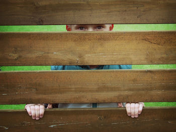 Boy hiding behind wooden fence