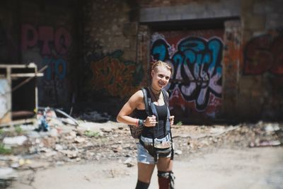 Portrait of young woman standing against graffiti