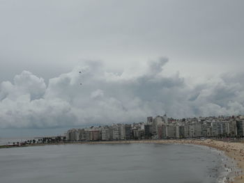 City at waterfront against cloudy sky