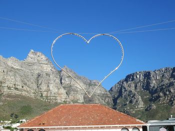 Heart shape decoration over house roof against clear blue sky