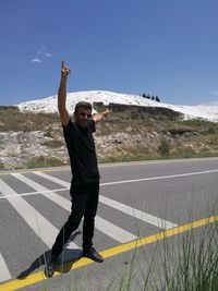 Full length of man standing on road against sky during sunny day