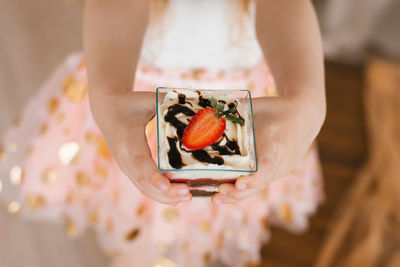 Sweet trifle dessert in the hands of a little girl on a holiday person