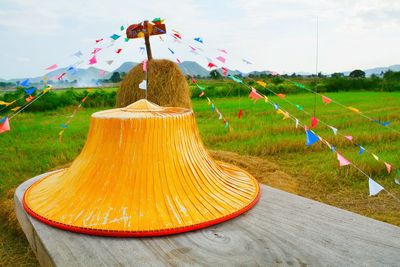 Close-up of multi colored umbrellas on field against sky