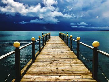 Wooden pier over sea against sky