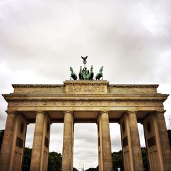 Low angle view of brandenburg gate against cloudy sky