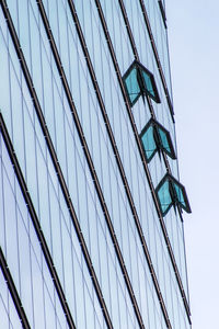 Low angle view of glass building against blue sky