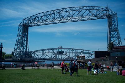 People in canal park visiting aerial lift bridge against sky