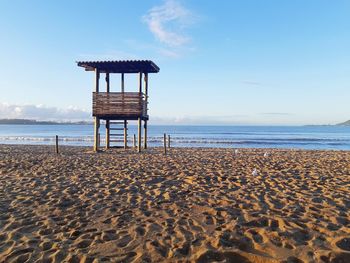 Lifeguard hut on beach against sky