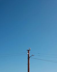 Low angle view of electricity pylon against blue sky