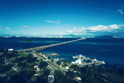 High angle view of city by sea against blue sky