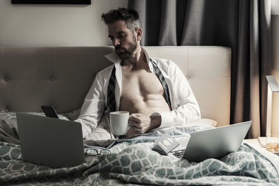 Man using mobile phone while sitting on bed