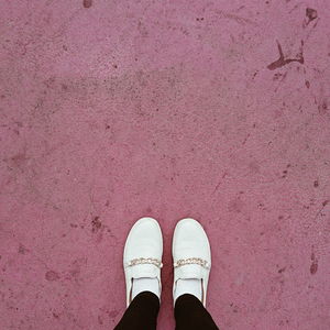 Low section of woman standing on pink footpath