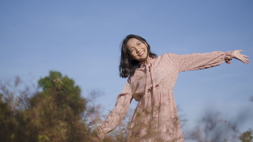 Low angle view of woman standing against blue sky