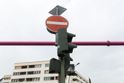 Low angle view of no entry sign board at road signal light against sky