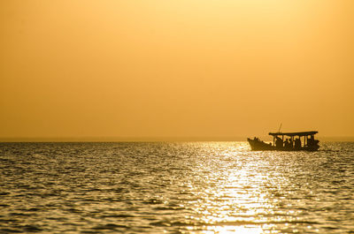 Silhouette boat in sea against clear sky during sunset