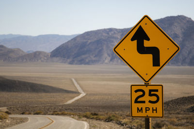 Curved roads and a mountain in the background and a yellow sign in the foreground in california