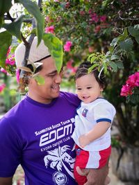 Portrait of smiling father and son standing against trees