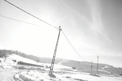 Ski lift over snow covered mountains against sky