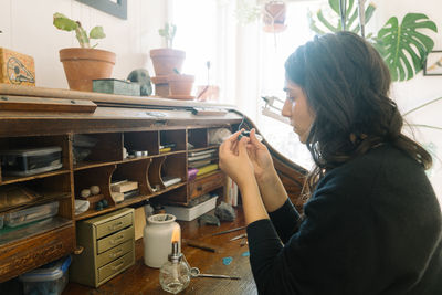 Female jewler focusing on creating small piece at home studio space