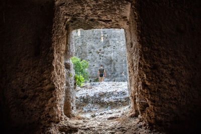 Man standing amidst stone wall