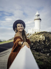 Portrait of smiling young woman standing against sky