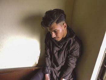 Young man looking away while sitting at home