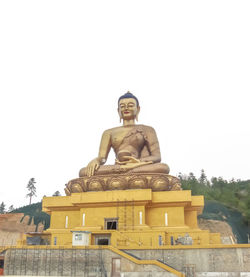 Low angle view of buddha statue against clear sky