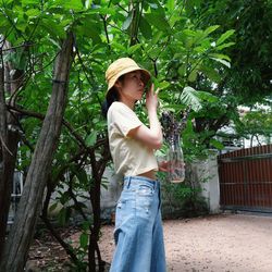 Side view of woman standing against trees