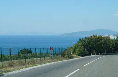 Road by sea against clear blue sky