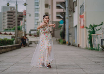 Woman with umbrella standing against built structure