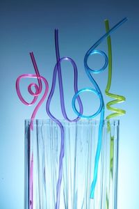 Close-up of colorful straws in glass against blue background