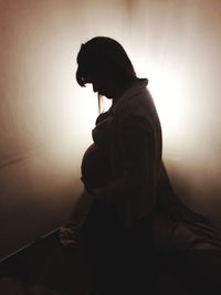 Side view of silhouette woman against wall