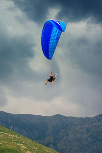 Low angle view of person paragliding against sky