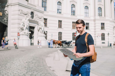 Portrait of young man standing on street in city