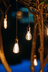 Low angle view of illuminated light bulbs hanging from ceiling